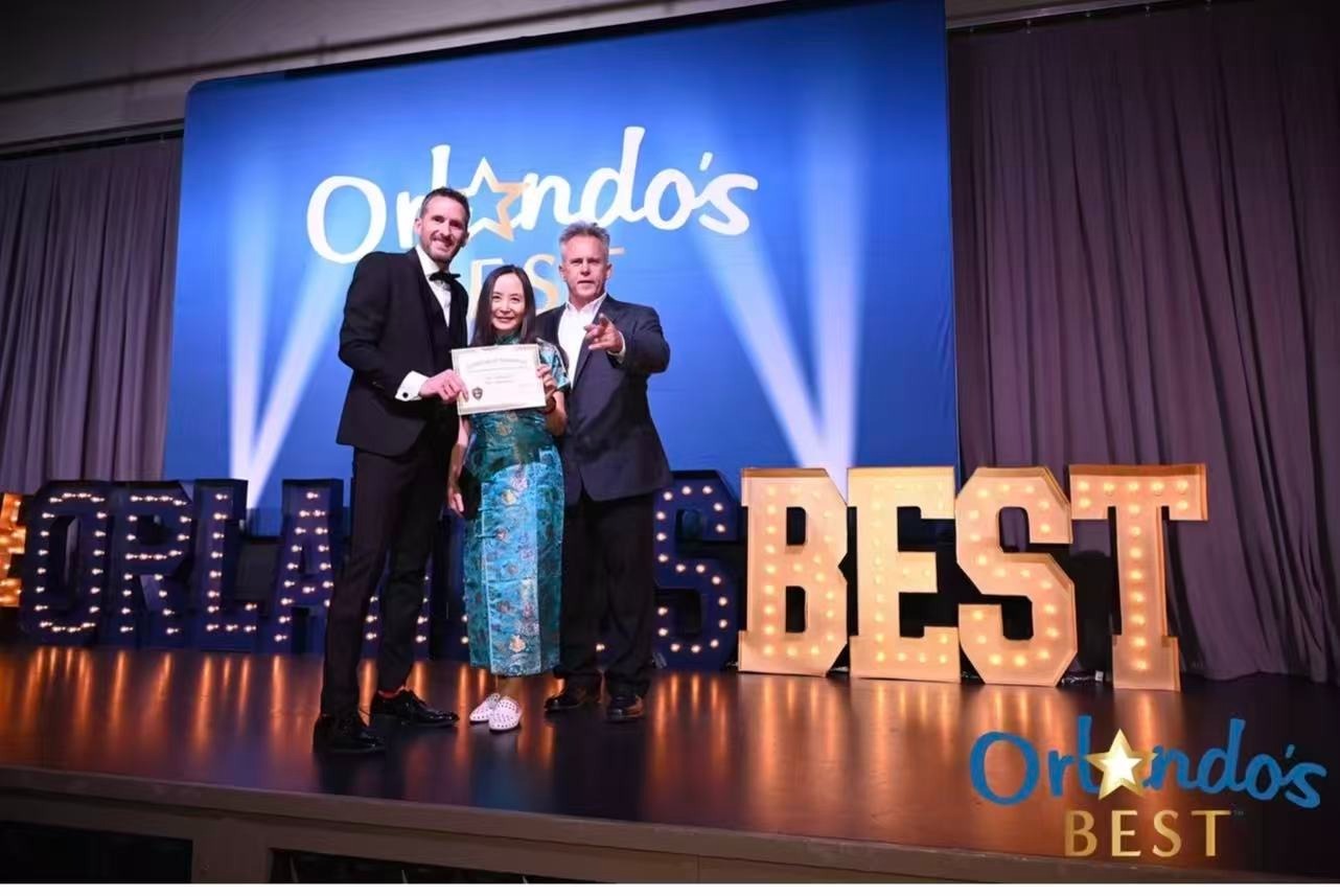 Dr. Qing Yi on stage at Orlando's Best 2024 award ceremony with presenters